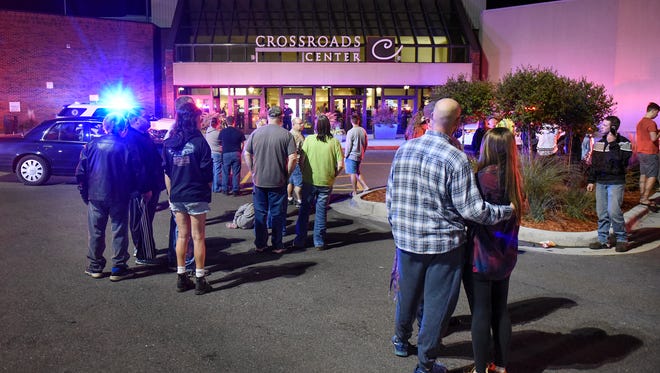 People stand near the entrance on the north side of Crossroads Center between Macy's and Target Saturday night as officials investigate a reported multiple stabbing incident.