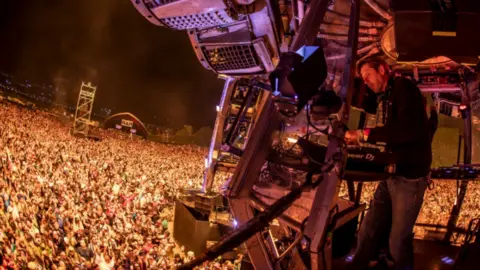 Charlie Raven Andy Cato performs a DJ set to a large crowd at Glastonbury Festival in 2022.