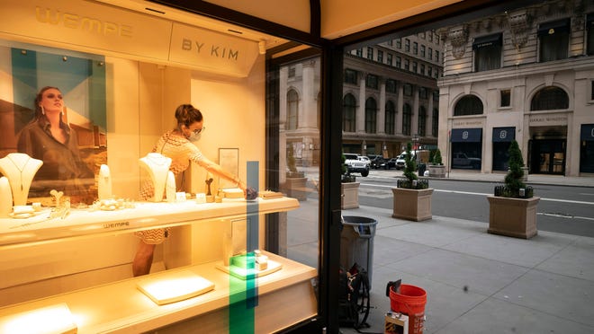 A Wempe store employee places jewellery in a store window in New York's Fifth Avenue shopping district. The jeweler is open for in-store and curbside pickup.