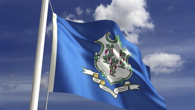 The Connecticut state flag flying in front of blue sky and white clouds.