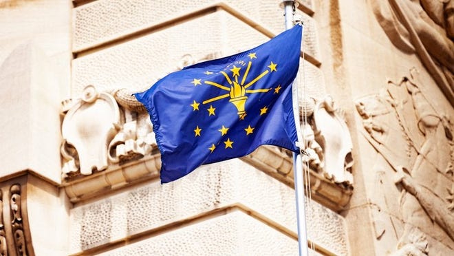 The Indiana state flag flying in front of a decorative building facade.