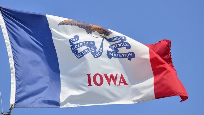 The Iowa state flag flying in front of a blue sky.