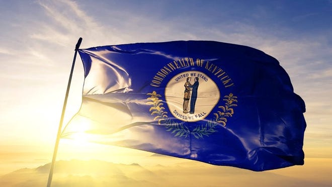 The Kentucky state flag flying in front of a sunny sky.
