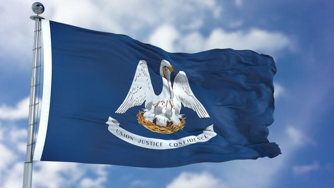 The Louisiana state flag flying in front of a blue sky and white clouds.