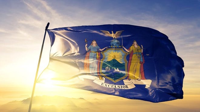The New York state flag flying in front of a bright sun.