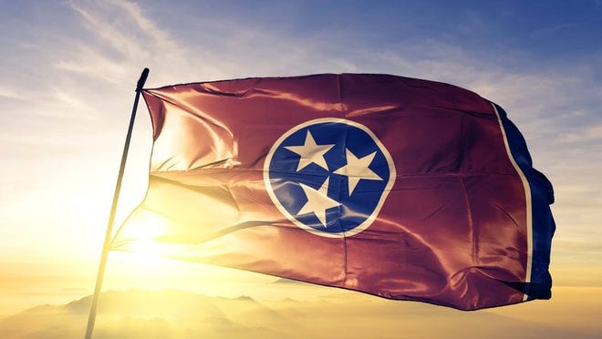 The Tennessee state flag flying in front of a sunny sky.