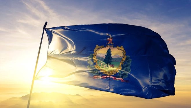 The Vermont state flag flying in front of a sunny sky.