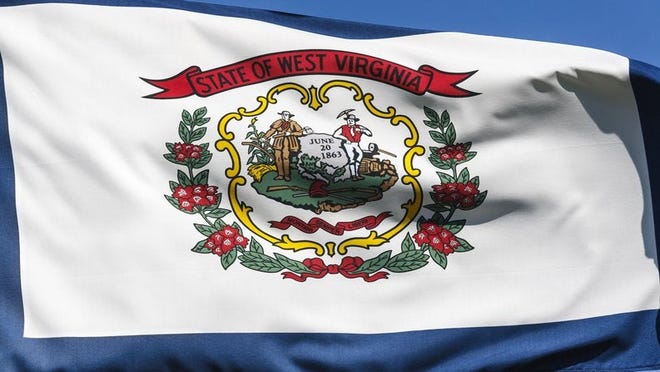 The West Virginia state flag flying in front of a blue sky.