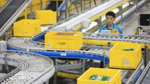 Getty Images Man next to conveyor belt in Alibaba fulfilment centre.