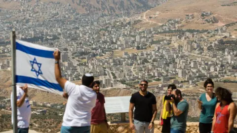 Getty Images Israeli students hold Israeli flag near West Bank settlement of Elon Moreh (file photo)