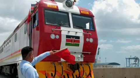 AFP Man waving a red flag during the launch of the first batch of Standard Gauge Railway freight locomotives at Mombasa Port - January 11, 2017