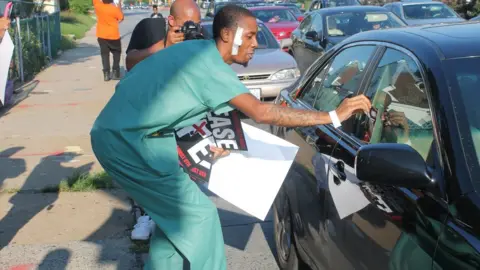 BBC Devrone McKnight passes flyers to a motorist