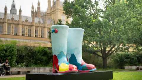 London Heritage Quarter A large sculpture of wellington boots outside the houses of parliament