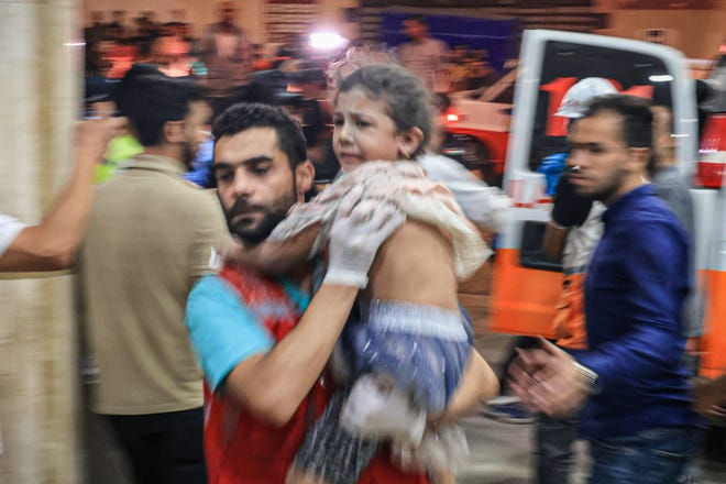 A Palestinian child injured in an Israeli air strike is carried inside the Nasser hospital in Khan Yunis in the southern of Gaza Strip, on October 17, 2023.