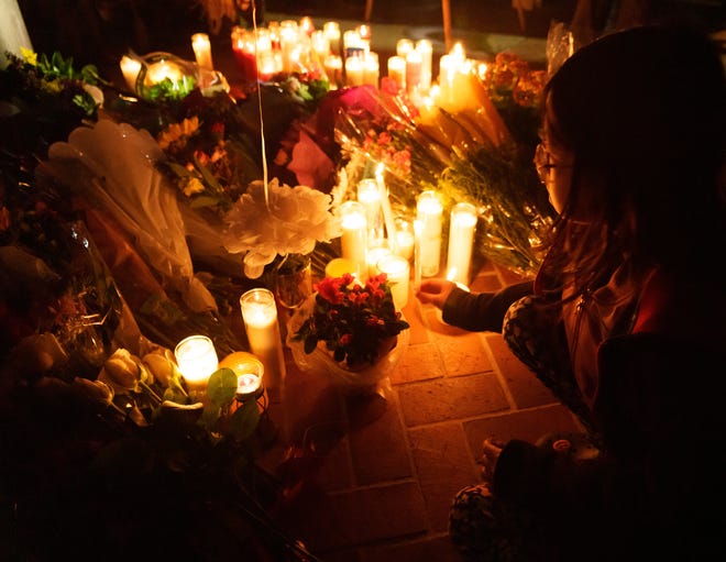 A young girl places a candle at a memorial in front of the Monterey City Hall during a vigil January 23, 2023. At least 11 people were killed and 10 others wounded in a shooting rampage at the Star Ballroom Dance Studio in Monterey Park, Calif. after a Lunar New Year celebration on Saturday, Jan. 21, 2023.
