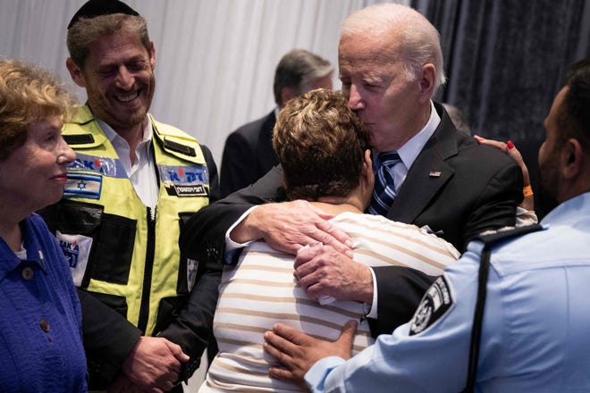 Police officer Evyatar Edri looks on as US President Joe Biden hugs his mother, Rachel Edri, who was held hostage by the Palestinian militant group Hamas, while meeting with people affected by this month's Hamas attack on Israel, on Oct. 18, 2023, in Tel Aviv. Thousands of Israeli and Palestinian people have died since October 7, 2023, after Palestinian Hamas militants based in the Gaza Strip entered southern Israel in a surprise attack, holding some people hostage, that led Israel to declare war on Hamas in Gaza on Oct. 8.