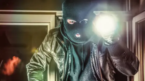 Getty Images Masked burglar holding torch