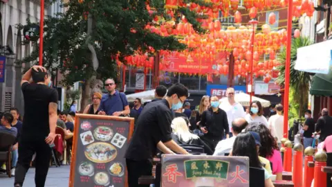 SOPA Images A waiter serves customers outside a restaurant in London's Chinatown during the Eat Out to Help Out scheme