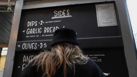 Nick Hartley/BBC Someone reading a chalk board menu