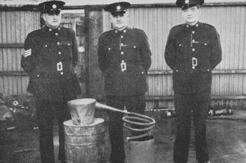 Donegal Historical Society Police officers stand next to a confiscated poitin still in the 20th Century