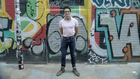 TikTok creator Roshan Salgado D'Arcy records a video on his smartphone while standing on the street