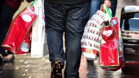 Getty Images A man is seen carrying multiple bags of Christmas shopping
