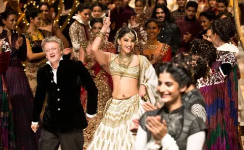 Getty Images Bollywood actress Sonam Kapoor shows clothes designed by Rohit Bal during Indian Bridal Fashion Week in 2013. Bal walks with her through a crowd