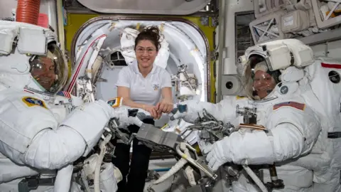 NASA Christina Koch (centre) assists fellow astronauts Nick Hague (left) and Anne McClain in their spacesuits