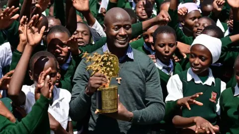 Getty Images Peter Tabichi with pupils and his award