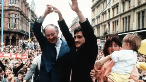 Pacemaker Barry McGuigan returns to Belfast with wife Sandra, son Blain and manager Barney Eastwood