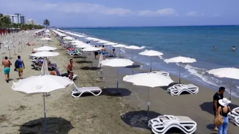 Getty Images People walking along a beach in Cyprus