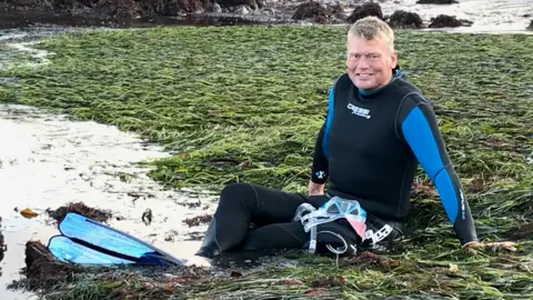 BBC Tom Heap sat in seagrass