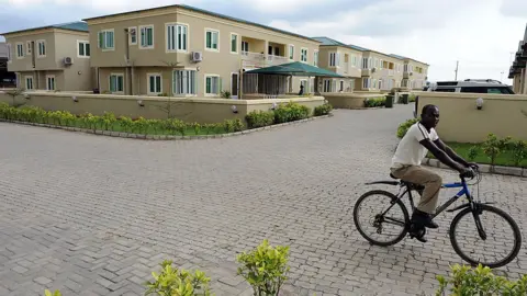 Getty Images A man rides a bicycle past a block of flats