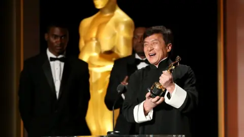 Getty Images Jackie Chan holds up his honorary Oscar