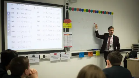 Getty Images A teacher talks to pupils during a maths lesson at the Ridings Federation Winterbourne International Academy in Winterbourne near Bristol