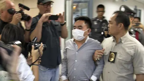 EPA Bach Van Minh, also known as Boonchai Bach (C), a Vietnamese national who also holds Thai citizenship, is escorted by Thai police officers at the Suvarnabhumi airport's police station in Samut Prakan province, on the outskirts of Bangkok, Thailand
