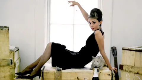 Shutterstock Audrey Hepburn lies on a packing case with her cat in the iconic black dress from Breakfast at Tiffany's