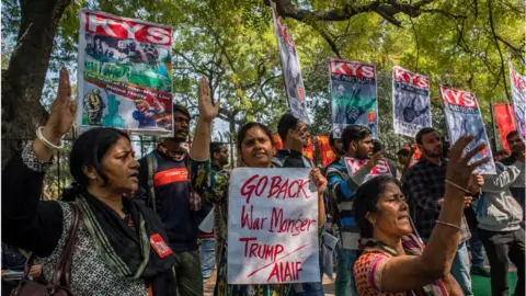 Getty Images Activists of All India Democratic Students Organisation (AIDSO) hold placards as they shout slogans against the arrival of US President during a protest demonstration against US President Donald Trump