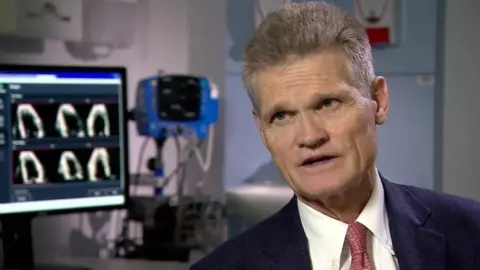 BBC Man in suit and tie sits by imaging machine