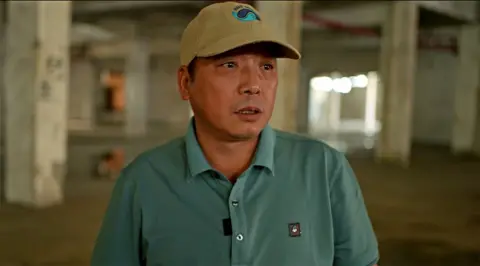 Xiqing Wang/BBC Ren Wenbing stands inside empty factory