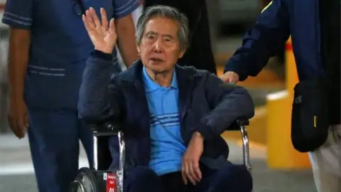 AFP Peru"s former President Alberto Fujimori waves to supporters as he is wheeled out of the Centenario Clinic in Lima on January 04, 2018