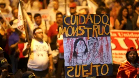 EPA Peruvians participate during a demonstration with a sign that reads 'Watch out - loose monster' with a cartoon of ex-president Alberto Fujimori and his daughter Keiko Fujimori in Lima, Peru, 11 January 2018
