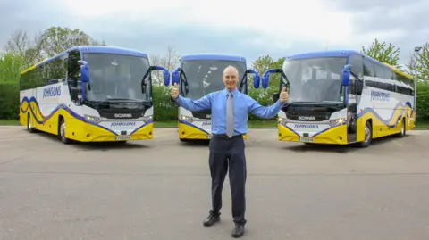 Johnsons Coaches A man standing in front of coaches