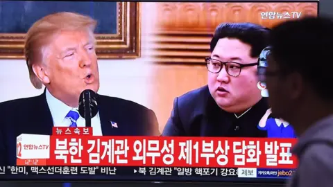 AFP / Getty Images A man walks past a television news screen showing North Korean leader Kim Jong Un (R) and US President Donald Trump (L) at a railway station in Seoul on 16 May 2018