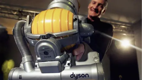 Bruno Vincent Sir James Dyson holds up a vacuum cleaner