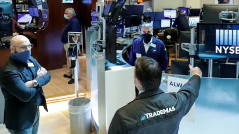 Reuters Traders wearing masks work, on the first day of in person trading since the closure during the outbreak of the coronavirus disease (COVID-19) on the floor at the NYSE in New York