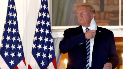Getty Images U.S. President Donald Trump removes his mask upon return to the White House from Walter Reed National Military Medical Center on October 05, 2020 in Washington, DC