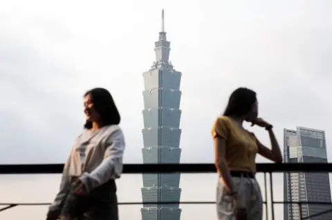 Getty Images People pose for photographs in front of the Taipei 101 building in Taipei, Taiwan, on Tuesday, Jan. 26, 2021.